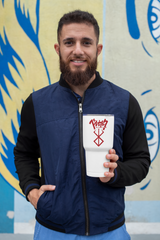 a man holding a cup in front of a painting