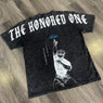 Black t-shirt with 'The Honored One' text and graphic on a wooden floor